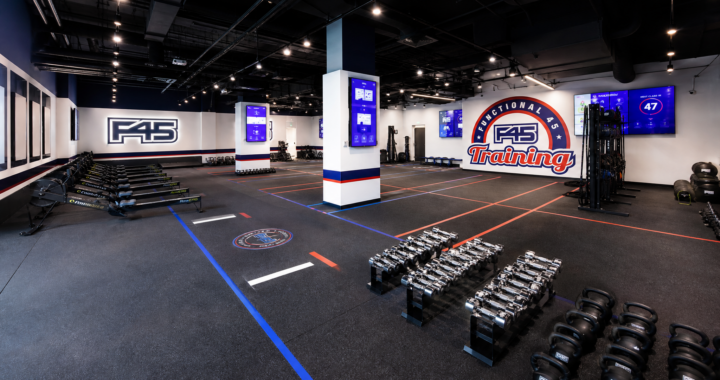 Modern F45 Training studio interior featuring blue, red, and white equipment, digital screens showing workouts, and a clean, high-energy functional training floor.