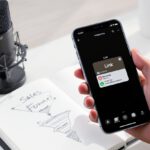 A smartphone held over a desk showing an Instagram Story edit with a Link sticker and a ManyChat DM automation notification.