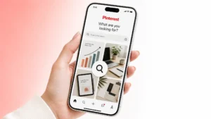 A smartphone showing the Pinterest search interface with a magnifying glass over business pins, illustrating market research.