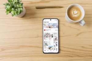 A high-end smartphone on a light oak desk showing a Pinterest 'Dream Life' board with affiliate sales charts.